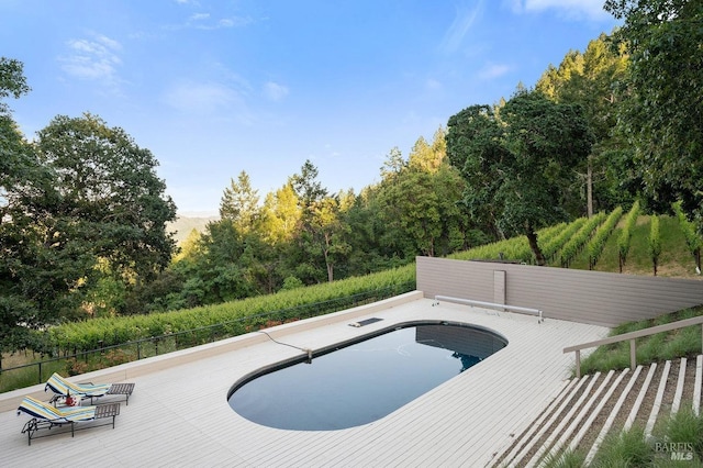 view of swimming pool featuring a wooden deck, a fenced in pool, and fence