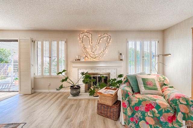 sitting room featuring plenty of natural light, a fireplace, a textured ceiling, and wood finished floors