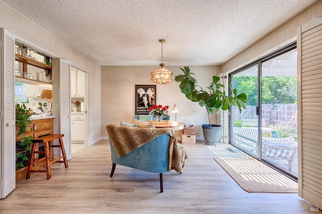 dining room with light wood finished floors, a chandelier, and a textured ceiling