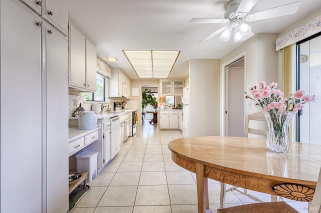 kitchen with white cabinetry, light countertops, light tile patterned floors, and white dishwasher