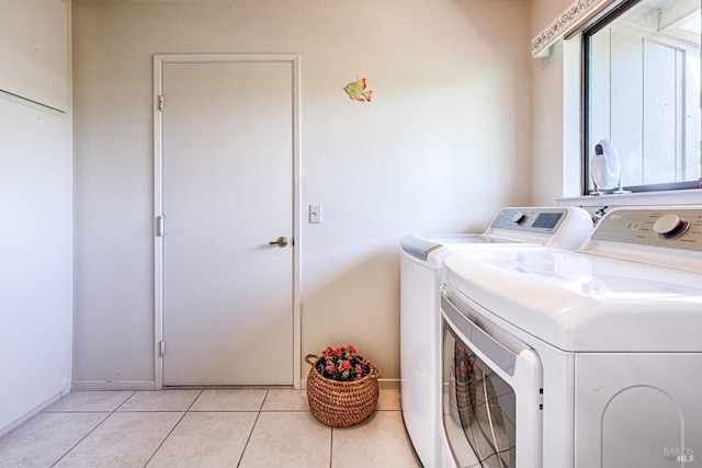 clothes washing area with washer and clothes dryer, laundry area, light tile patterned flooring, and baseboards