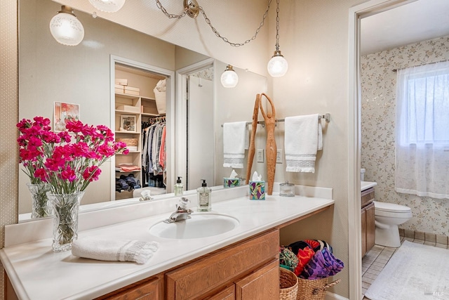 full bathroom featuring toilet, wallpapered walls, tile patterned flooring, vanity, and a spacious closet