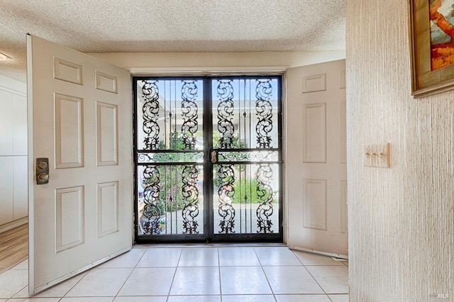 entryway with a textured ceiling, light tile patterned flooring, and french doors