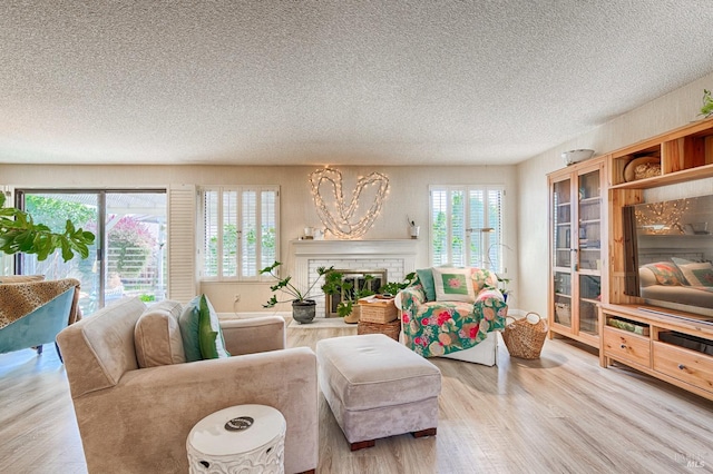 living area featuring a textured ceiling, wood finished floors, and a brick fireplace