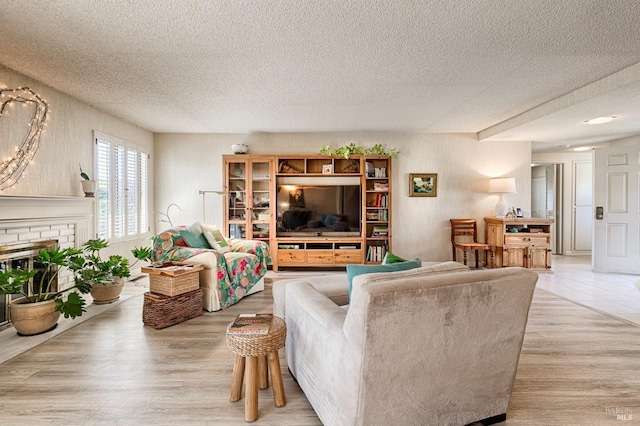 living area with a textured ceiling, a brick fireplace, and light wood-type flooring