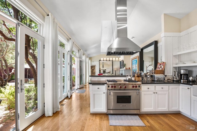 kitchen featuring a peninsula, light wood finished floors, dark countertops, ventilation hood, and premium stove