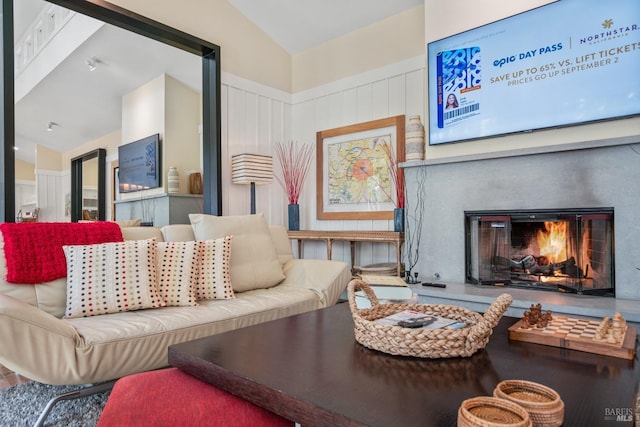 living room with a glass covered fireplace and vaulted ceiling