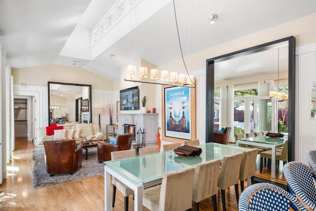 dining space with an inviting chandelier, lofted ceiling, and wood finished floors