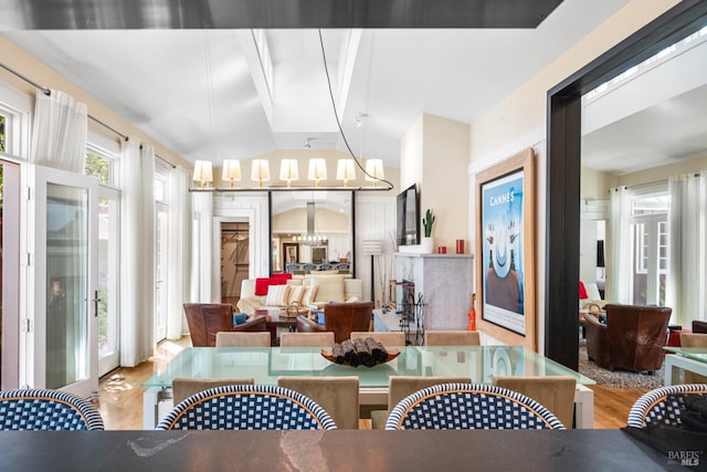 dining room with an inviting chandelier, wood finished floors, and vaulted ceiling