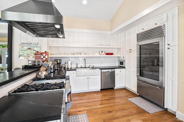 kitchen with a sink, dark countertops, stainless steel appliances, white cabinets, and exhaust hood