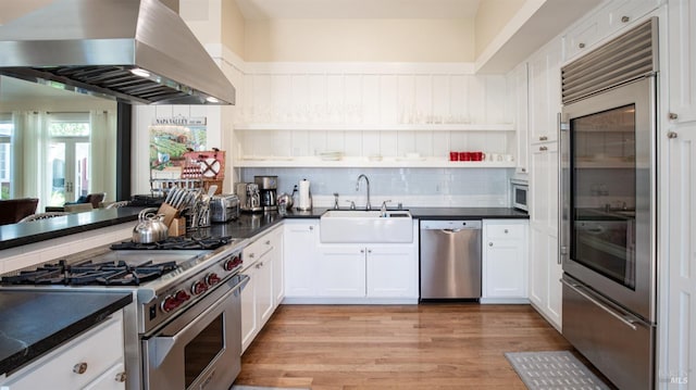 kitchen featuring premium appliances, dark countertops, and exhaust hood