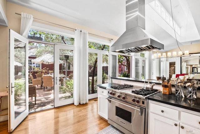 kitchen featuring a healthy amount of sunlight, island exhaust hood, dark countertops, and luxury range