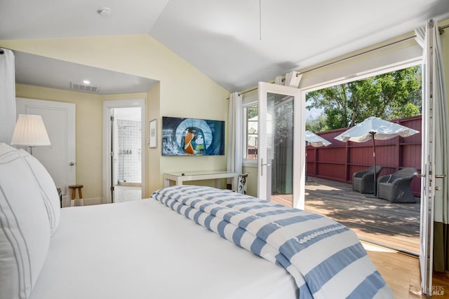 bedroom featuring ensuite bathroom, wood finished floors, visible vents, vaulted ceiling, and access to exterior