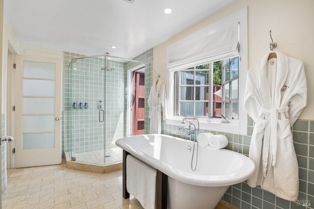 bathroom with a shower stall, tile walls, a soaking tub, and recessed lighting