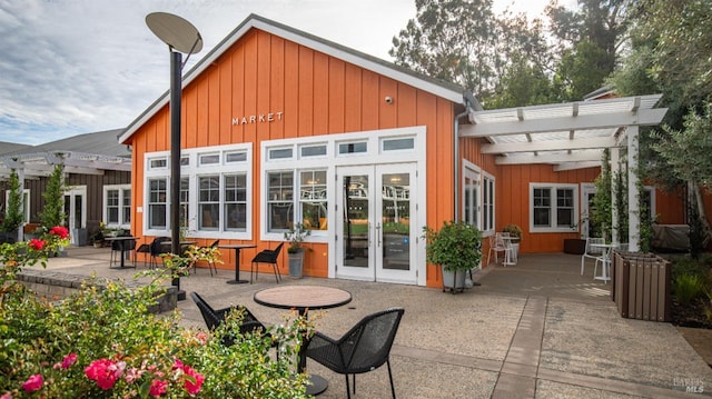 rear view of property with a pergola, a patio, french doors, and board and batten siding