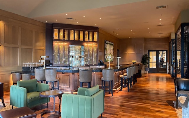 bar featuring a community bar, french doors, visible vents, and wood finished floors