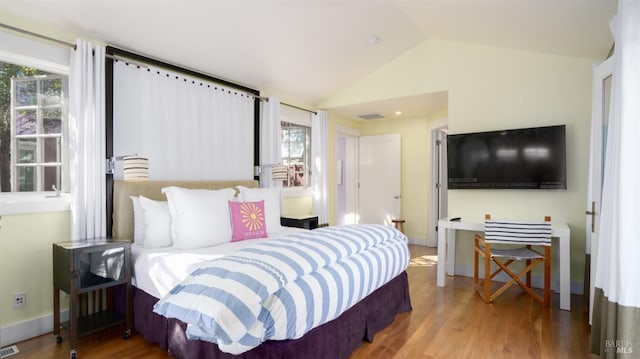 bedroom with baseboards, vaulted ceiling, wood finished floors, and visible vents