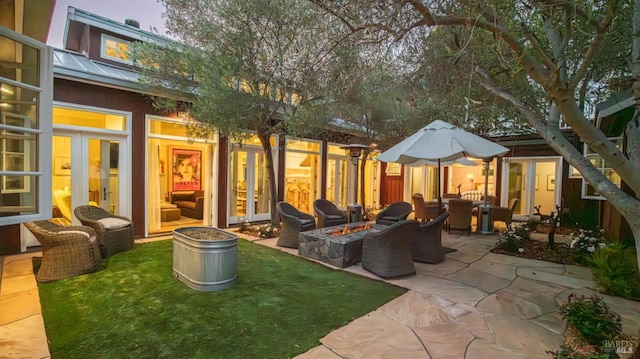 rear view of house featuring metal roof, an outdoor fire pit, and a patio