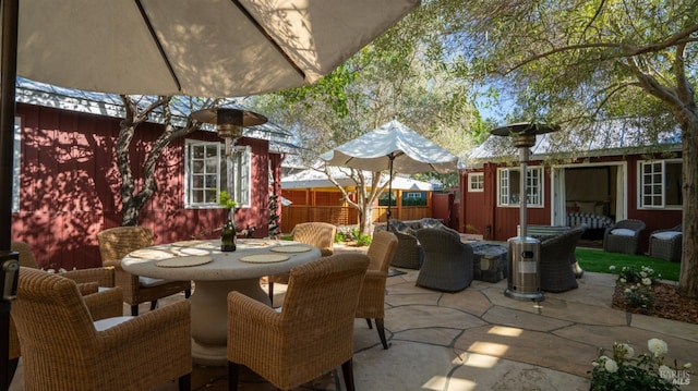 view of patio / terrace featuring a fenced backyard, outdoor dining area, and an outbuilding
