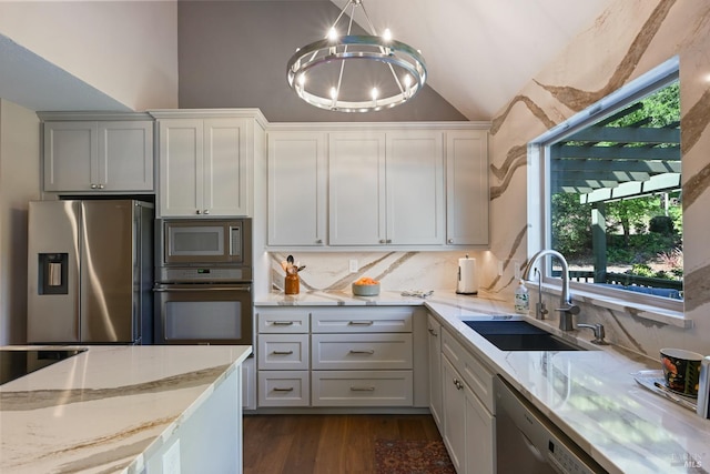 kitchen featuring an inviting chandelier, a sink, decorative backsplash, vaulted ceiling, and stainless steel appliances