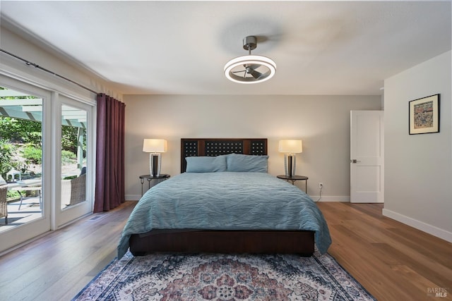 bedroom featuring baseboards, access to outside, and wood finished floors
