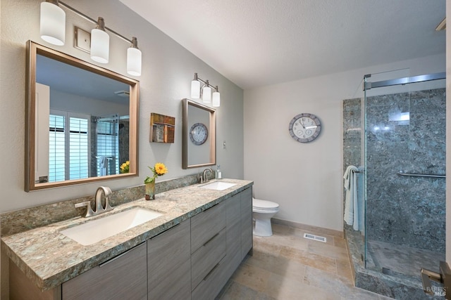 full bath featuring a sink, double vanity, toilet, and a stall shower