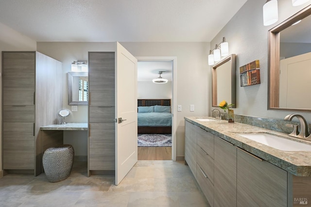 bathroom featuring double vanity, connected bathroom, baseboards, and a sink