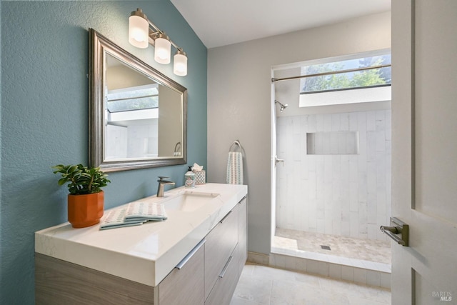 full bathroom featuring a tile shower, tile patterned floors, vanity, and a textured wall