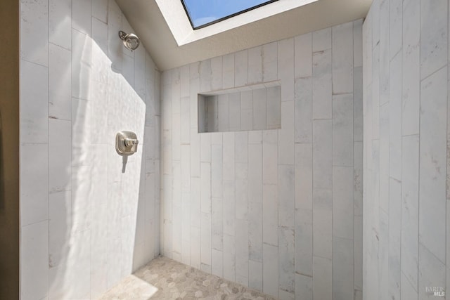 bathroom with a skylight and tiled shower