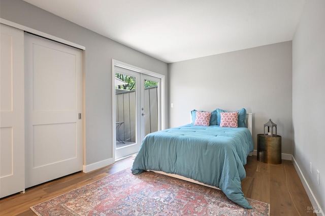 bedroom with baseboards, wood finished floors, and access to exterior
