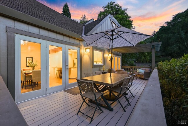 deck at dusk with outdoor lounge area, outdoor dining space, and french doors