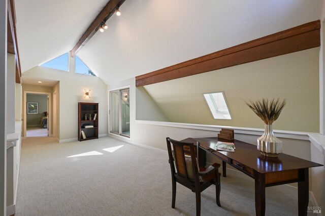 carpeted office space featuring track lighting, baseboards, and vaulted ceiling with skylight