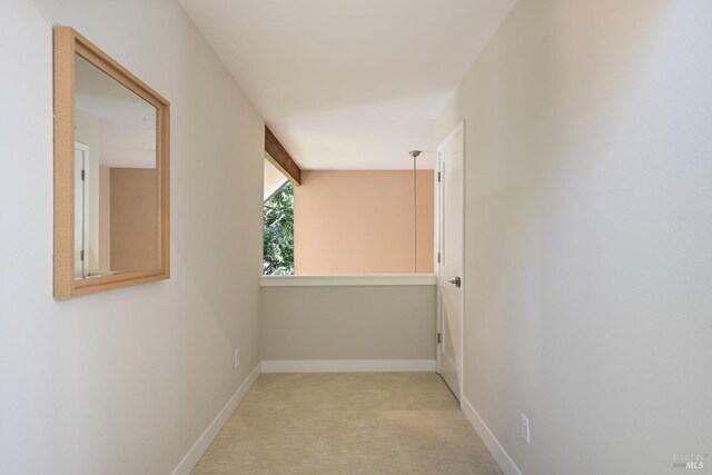 hall featuring baseboards and light colored carpet