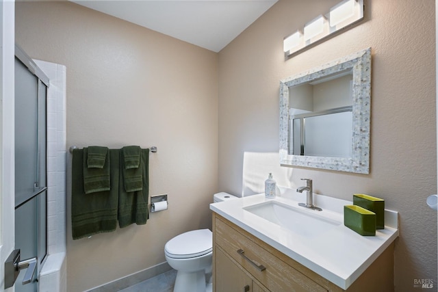 full bath featuring a shower with shower door, vanity, toilet, and baseboards