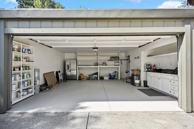 garage featuring stainless steel fridge with ice dispenser, visible vents, and a garage door opener
