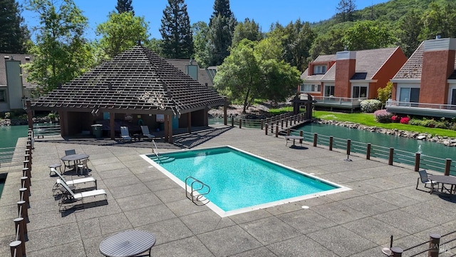community pool featuring a patio, a water view, and a gazebo