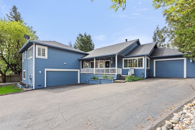 view of front facade with a porch, aphalt driveway, a garage, and fence