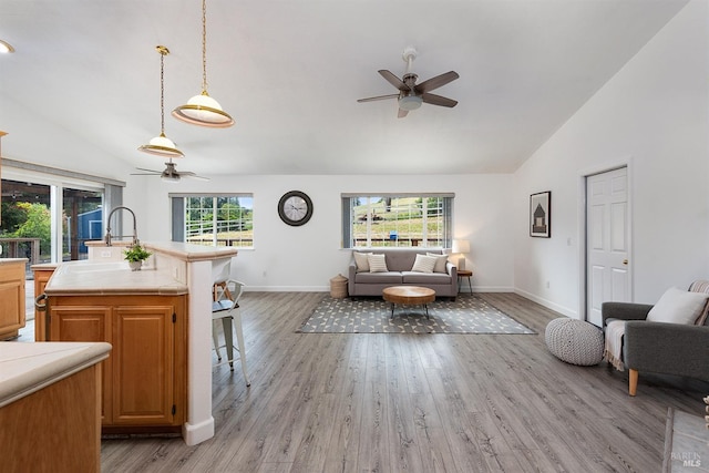 living room featuring light wood-type flooring, baseboards, ceiling fan, and vaulted ceiling