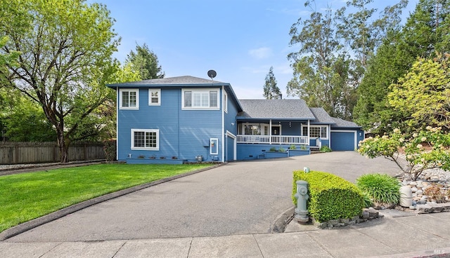 split level home featuring fence, an attached garage, a front yard, a porch, and aphalt driveway
