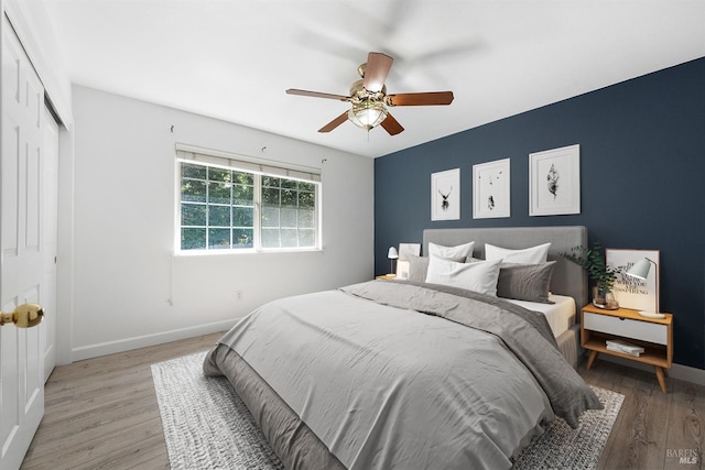 bedroom with baseboards, a closet, light wood-type flooring, and a ceiling fan
