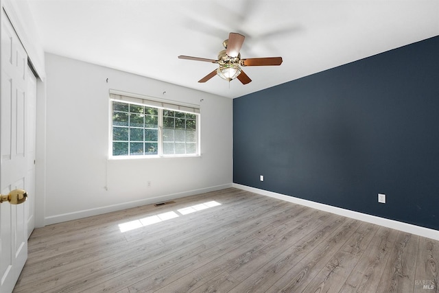 spare room with ceiling fan, baseboards, visible vents, and wood finished floors