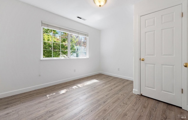 empty room featuring baseboards, visible vents, and light wood-style floors