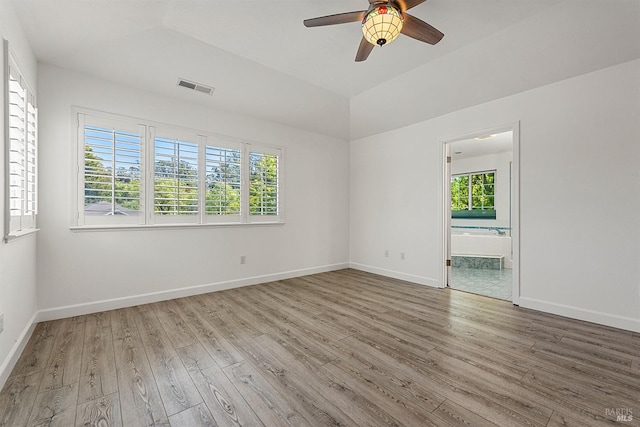spare room featuring a healthy amount of sunlight, visible vents, and wood finished floors