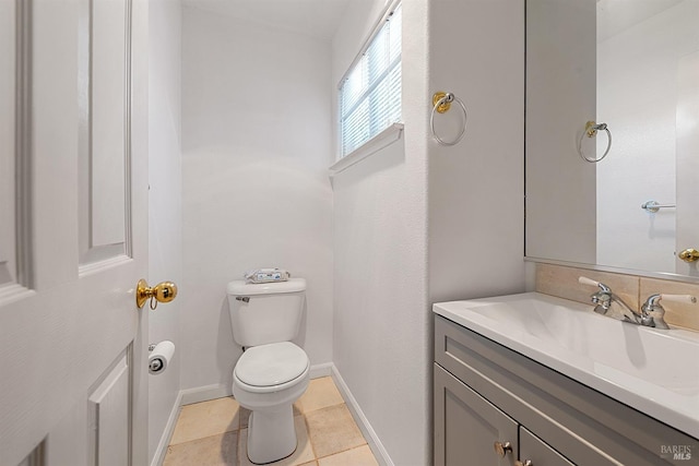 half bath with vanity, toilet, baseboards, and tile patterned flooring