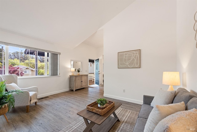 living area featuring wood finished floors, visible vents, baseboards, and high vaulted ceiling