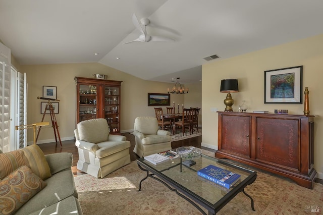 living area featuring vaulted ceiling, visible vents, baseboards, and ceiling fan with notable chandelier