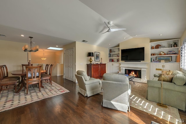 living area featuring a lit fireplace, dark wood finished floors, visible vents, built in shelves, and lofted ceiling