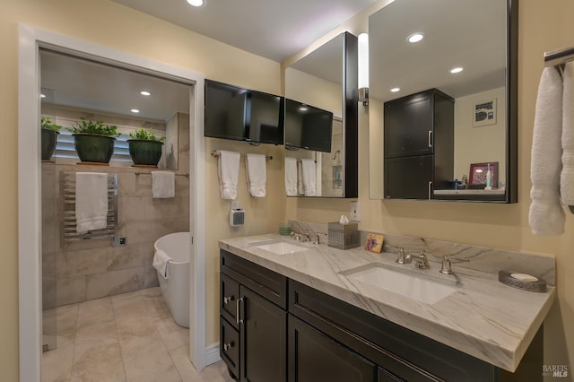 full bathroom featuring a sink, a freestanding bath, tile walls, and double vanity