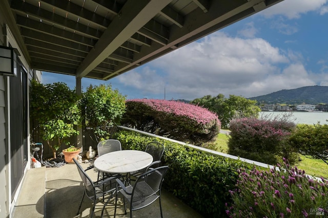 balcony with a water and mountain view and outdoor dining area