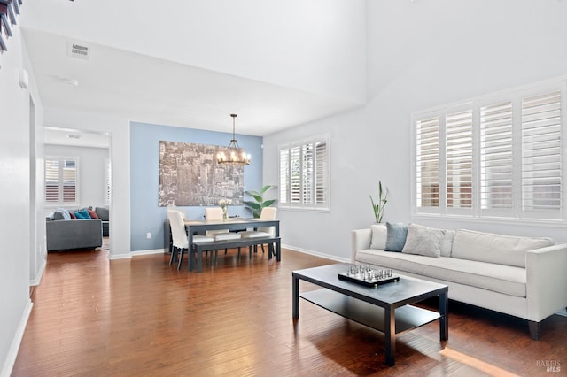 living area with a chandelier, baseboards, visible vents, and wood finished floors